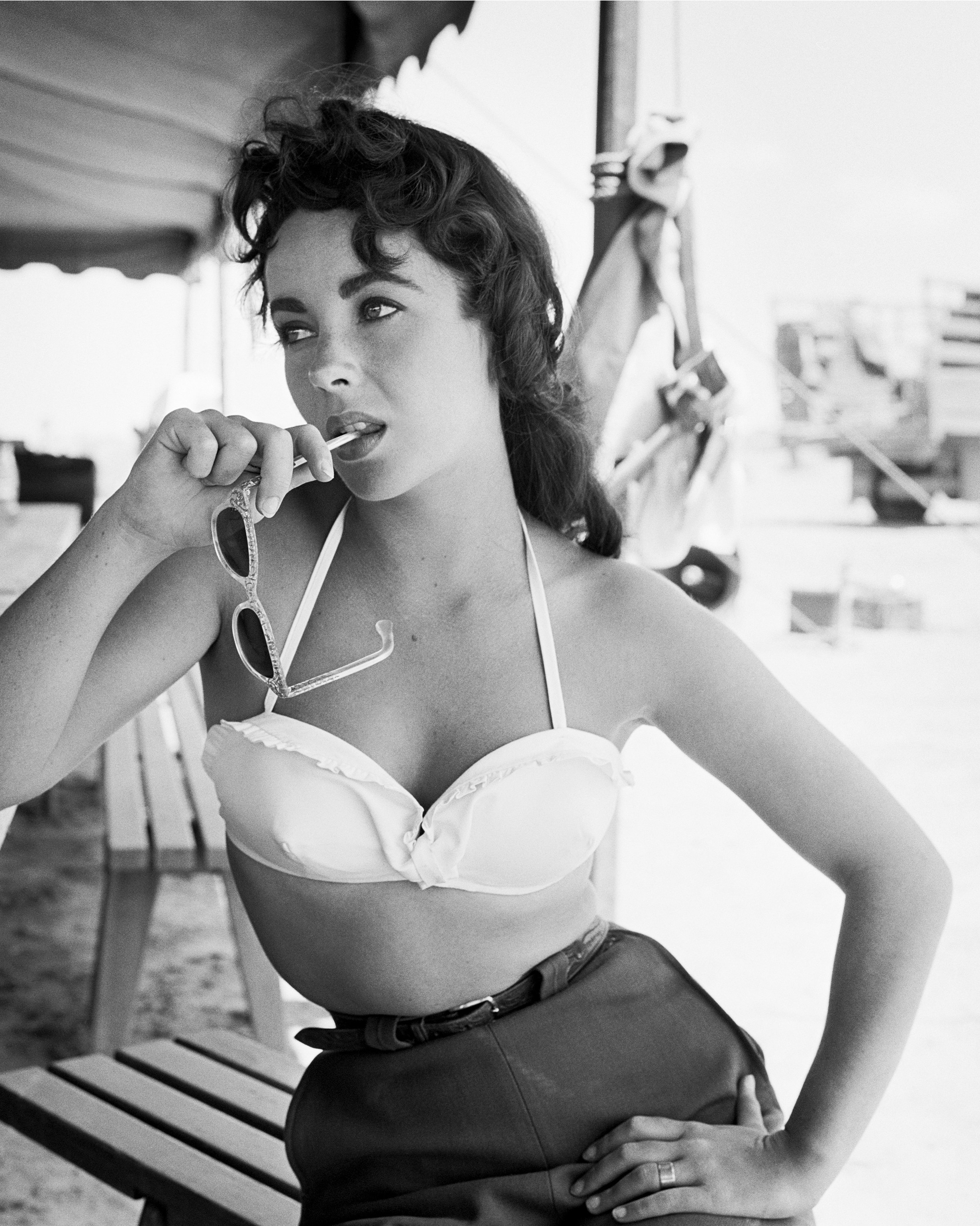 NOVEMBER 24: Actress Elizabeth Taylor teases with sunglasses in her mouth as she poses on the set of the movie 'Giant' which was released on November 24, 1956. (Photo by Frank Worth, Courtesy of Emage International/Getty Images)
