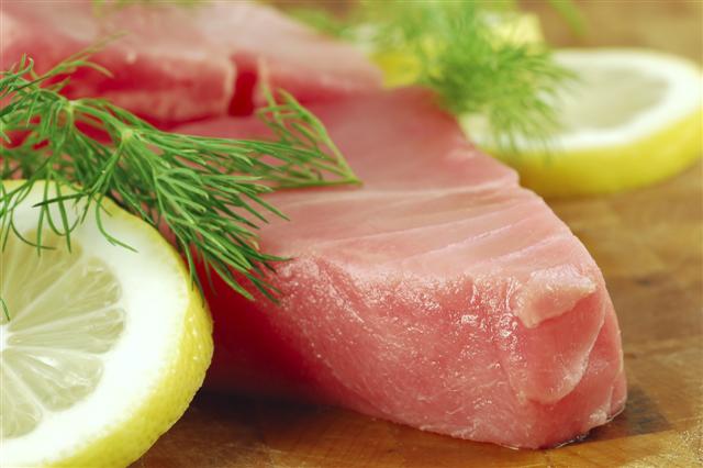 Fresh tuna steaks with lemon and dill on a cutting board