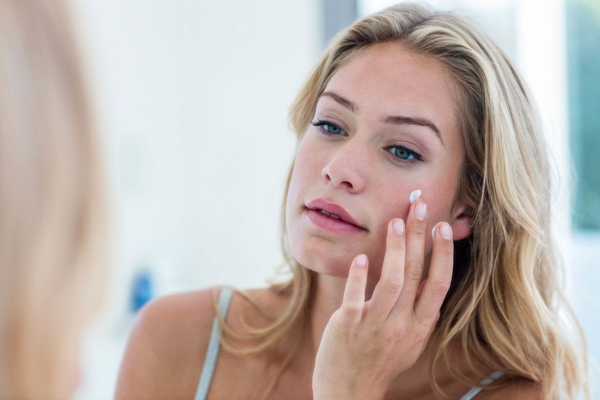 smiling-pretty-woman-applying-cream-on-her-face-royalty-free-image-846330444-1549392244